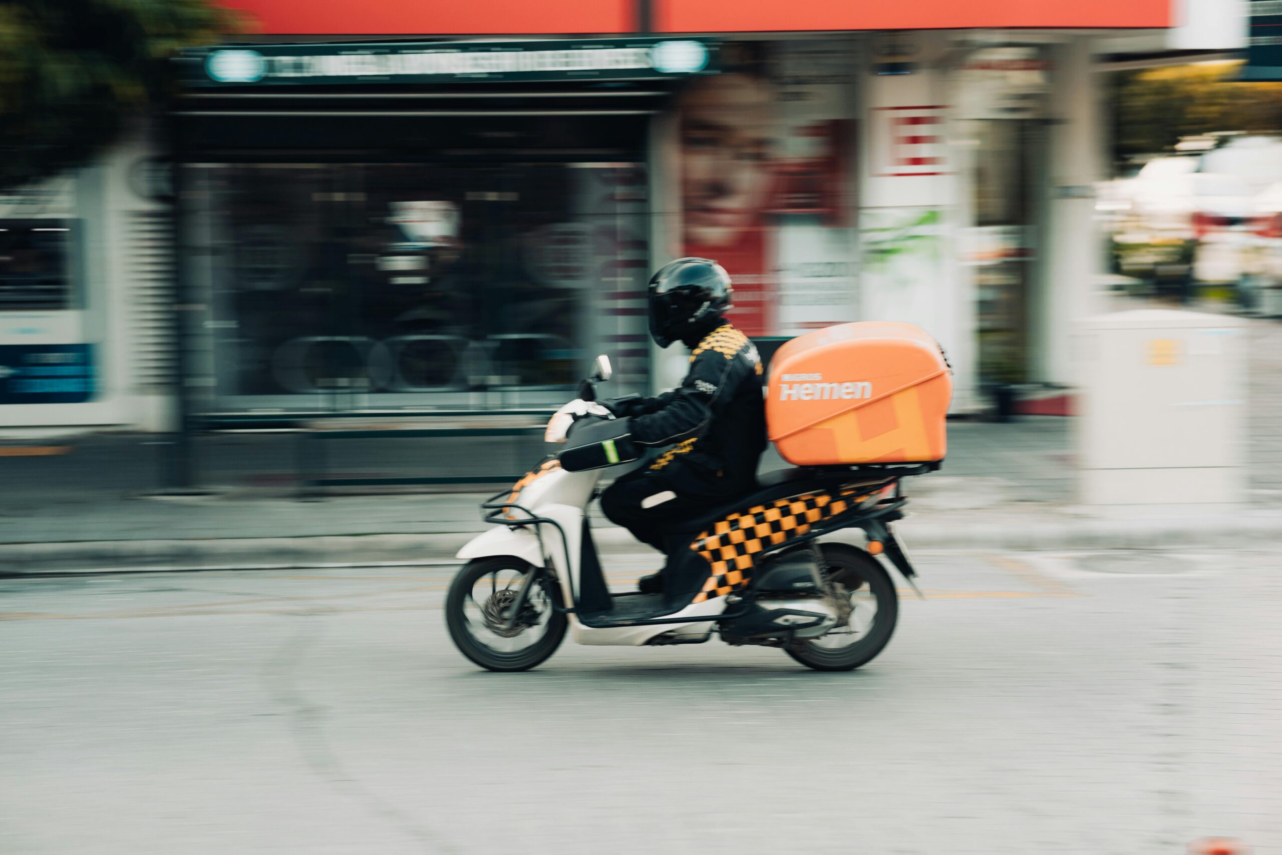 Home A delivery rider on a motor scooter speeds through city streets capturing urban transportation dynamics.
