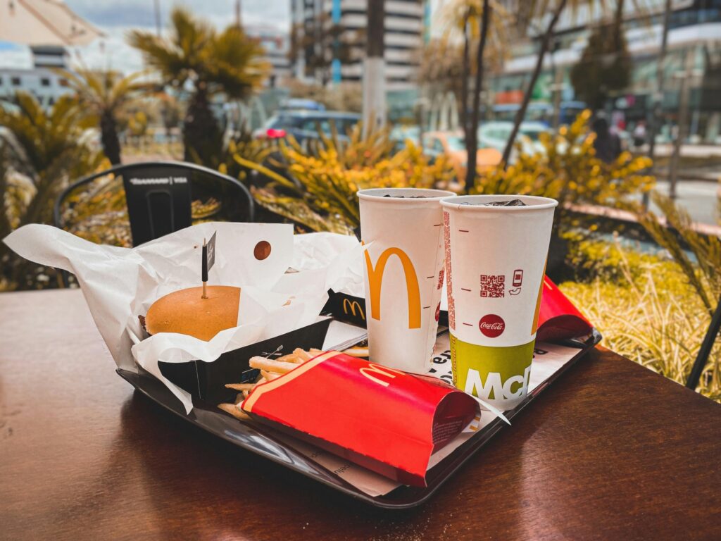 Home An appetizing fast food meal with burger, french fries, and drinks on an outdoor table in urban setting.
